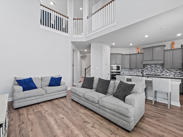 living room with stairs, baseboards, wood finished floors, and recessed lighting