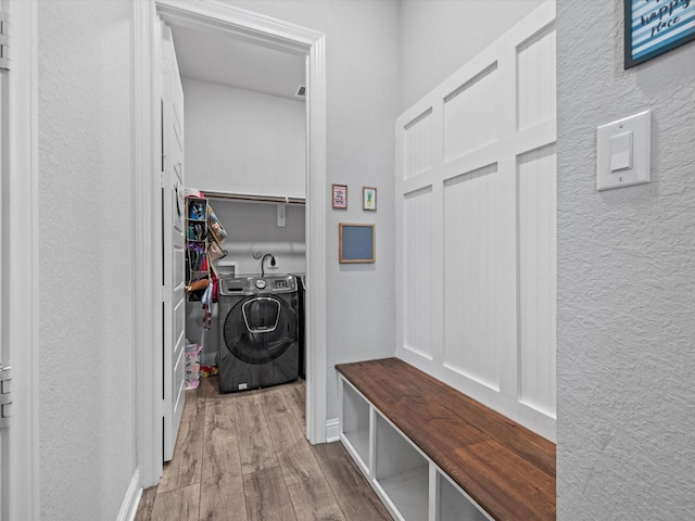 mudroom featuring a textured wall, washing machine and clothes dryer, and wood finished floors