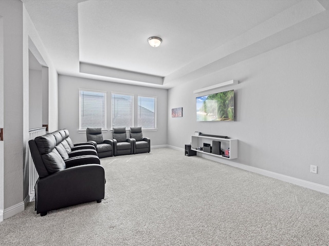 carpeted living room featuring a tray ceiling and baseboards