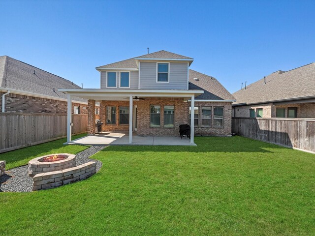 rear view of property with a fire pit, a yard, brick siding, and a fenced backyard