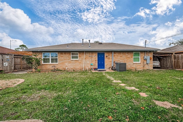 rear view of property with central air condition unit and a yard