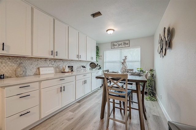 kitchen with backsplash, white cabinets, and light hardwood / wood-style floors