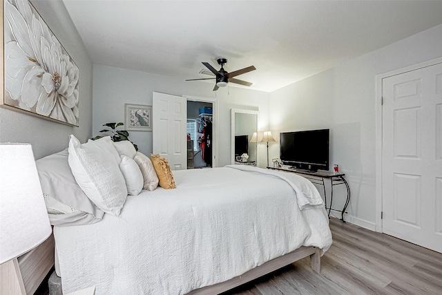 bedroom featuring hardwood / wood-style floors, ceiling fan, a spacious closet, and a closet