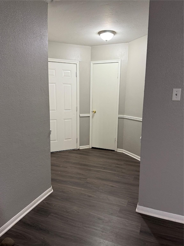 hallway featuring a textured ceiling and dark hardwood / wood-style flooring