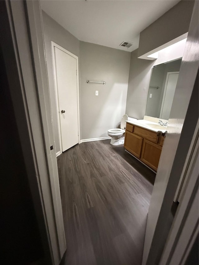 bathroom featuring wood-type flooring, vanity, and toilet