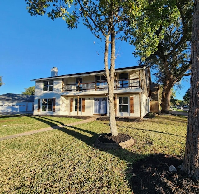 rear view of house with a lawn, a balcony, and french doors