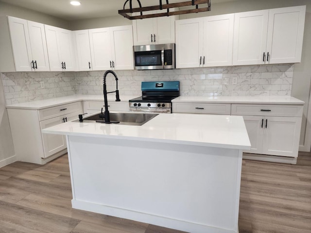 kitchen featuring white cabinets, stainless steel appliances, and an island with sink