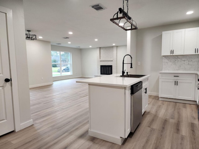 kitchen featuring white cabinetry, tasteful backsplash, a kitchen island with sink, and sink