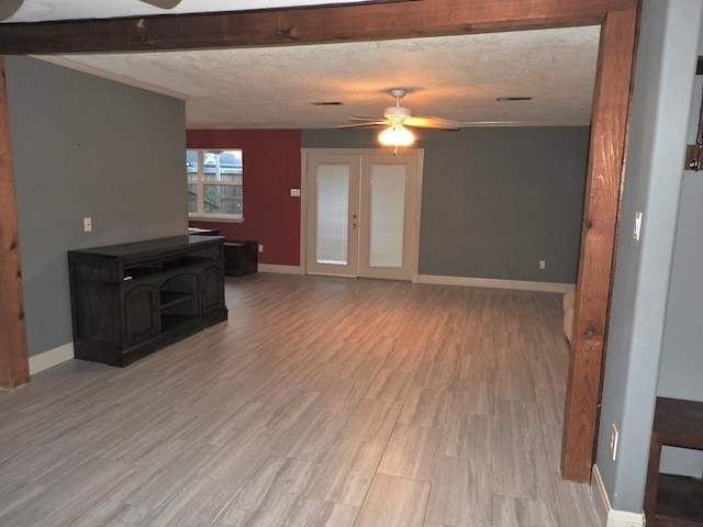 living room featuring ceiling fan, a wood stove, a textured ceiling, and light hardwood / wood-style flooring