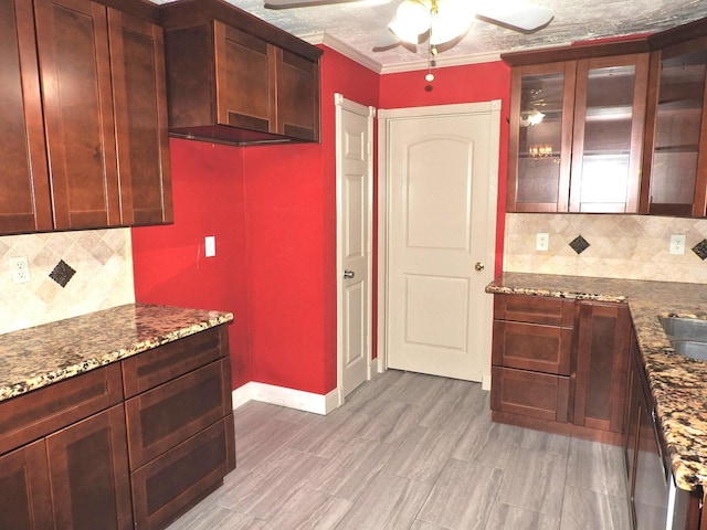 kitchen with decorative backsplash, sink, crown molding, and stone counters