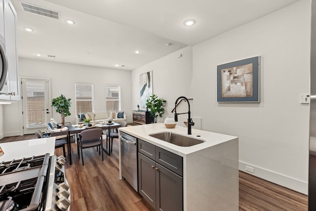 kitchen featuring sink, gray cabinetry, a center island with sink, appliances with stainless steel finishes, and dark hardwood / wood-style floors