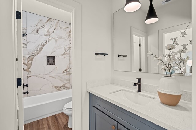 full bathroom with vanity, tiled shower / bath combo, wood-type flooring, and toilet