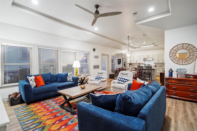 living room featuring ceiling fan, a raised ceiling, and light hardwood / wood-style flooring