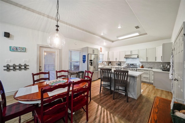 dining room with a raised ceiling and dark hardwood / wood-style flooring