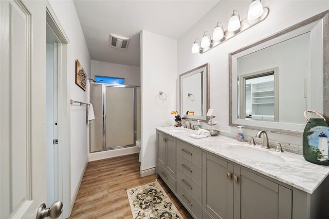 bathroom with vanity, toilet, an enclosed shower, and wood-type flooring