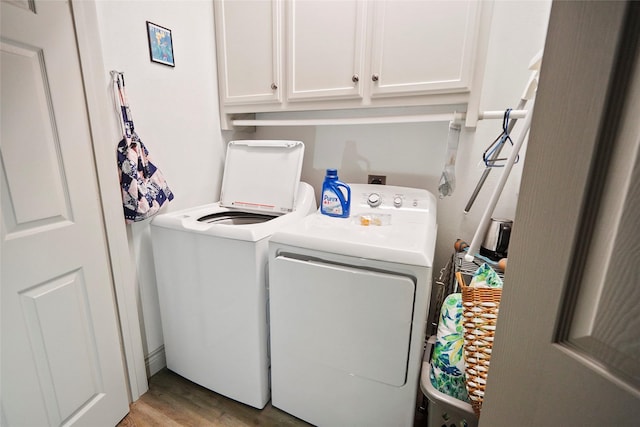 clothes washing area featuring washing machine and clothes dryer, cabinets, and light hardwood / wood-style floors