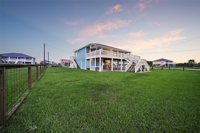 back house at dusk with a wooden deck and a lawn