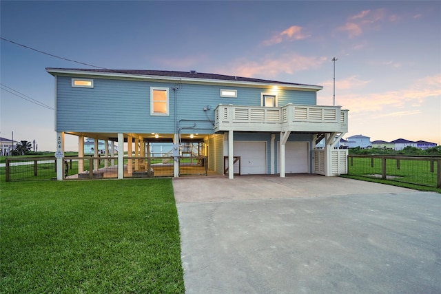 back house at dusk with a carport, a garage, a yard, and a balcony