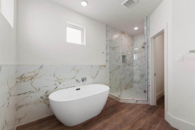 bathroom featuring hardwood / wood-style flooring, separate shower and tub, and tile walls