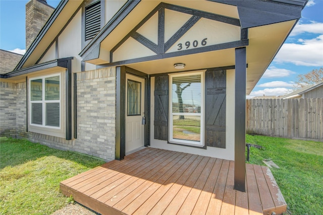 entrance to property featuring a deck and a lawn