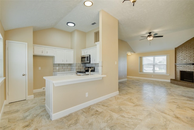 kitchen with lofted ceiling, appliances with stainless steel finishes, tasteful backsplash, and white cabinetry