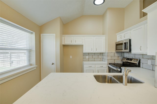 kitchen with white cabinetry, appliances with stainless steel finishes, backsplash, vaulted ceiling, and sink