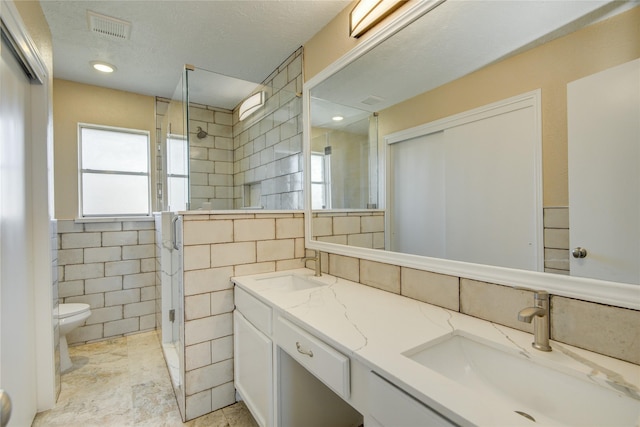 bathroom featuring toilet, vanity, tile walls, a textured ceiling, and an enclosed shower