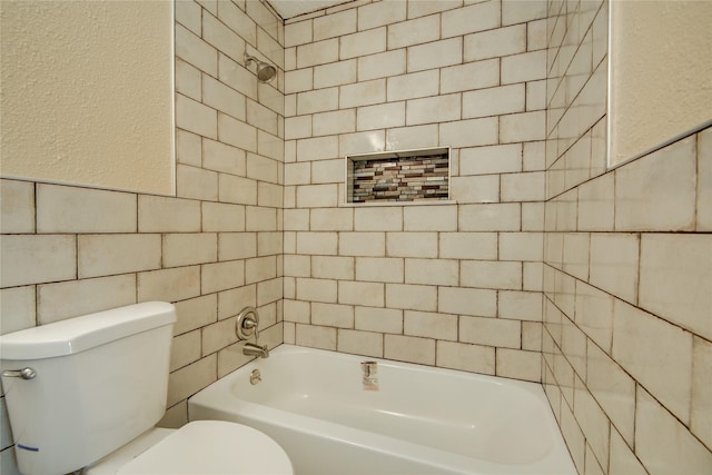 bathroom with toilet, tile walls, and tiled shower / bath