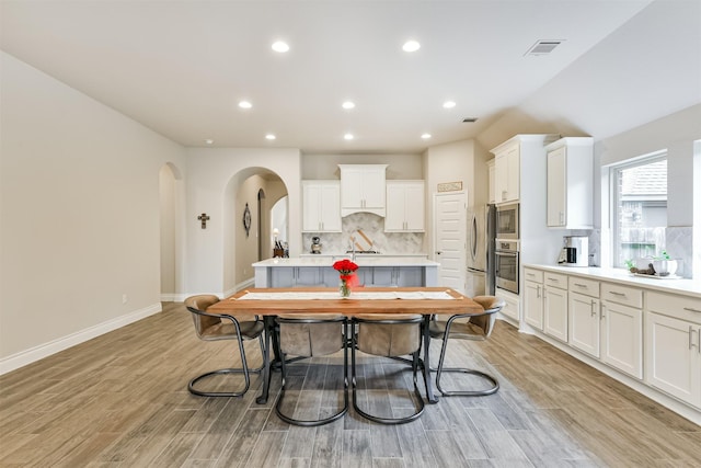 kitchen with decorative backsplash, light wood-type flooring, white cabinetry, and appliances with stainless steel finishes