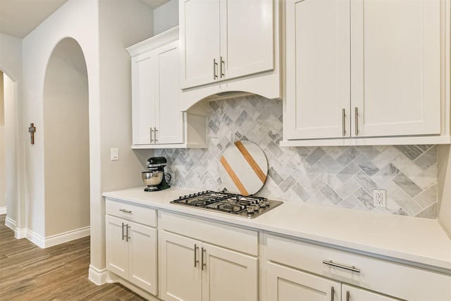 kitchen with white cabinets, light hardwood / wood-style flooring, stainless steel gas cooktop, and tasteful backsplash