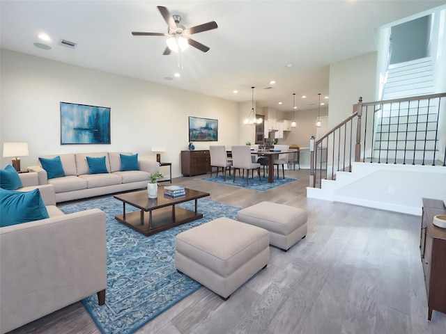 living room with wood-type flooring and ceiling fan with notable chandelier