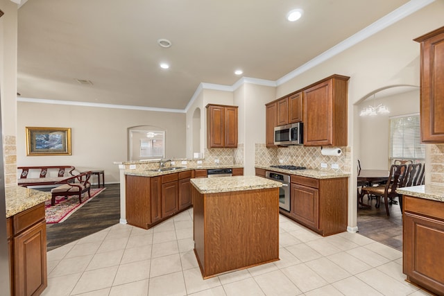 kitchen with kitchen peninsula, appliances with stainless steel finishes, light stone counters, a kitchen island, and light tile patterned flooring