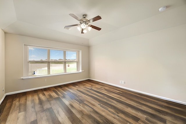 empty room featuring dark hardwood / wood-style flooring, a tray ceiling, and ceiling fan