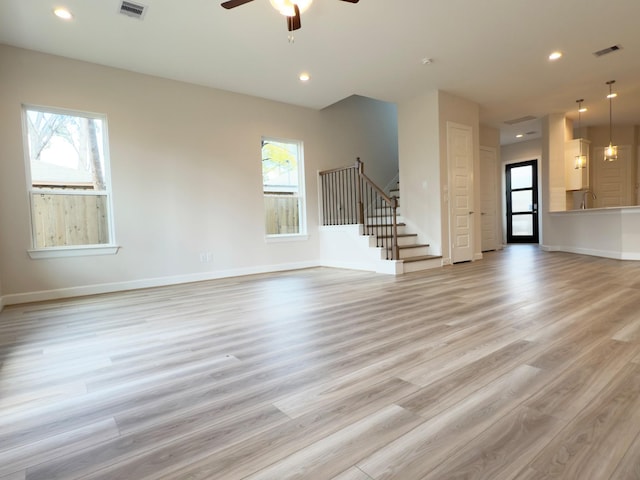 unfurnished living room featuring ceiling fan, plenty of natural light, and light wood-type flooring