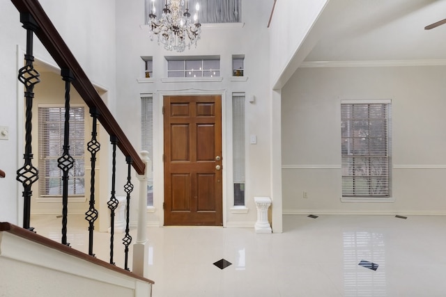 tiled foyer featuring ornamental molding, a high ceiling, and a notable chandelier