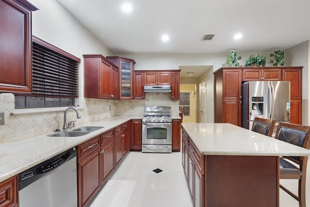 kitchen featuring sink, backsplash, a kitchen bar, light tile patterned floors, and stainless steel appliances