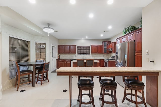 kitchen with sink, a breakfast bar area, backsplash, stainless steel appliances, and kitchen peninsula