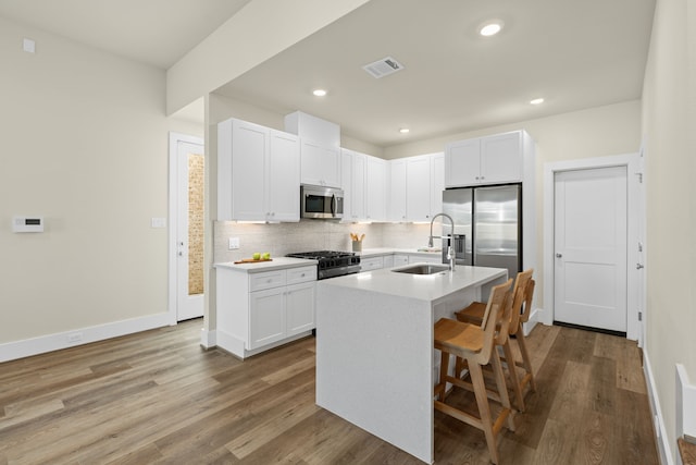 kitchen with stainless steel appliances, sink, a center island with sink, and white cabinets