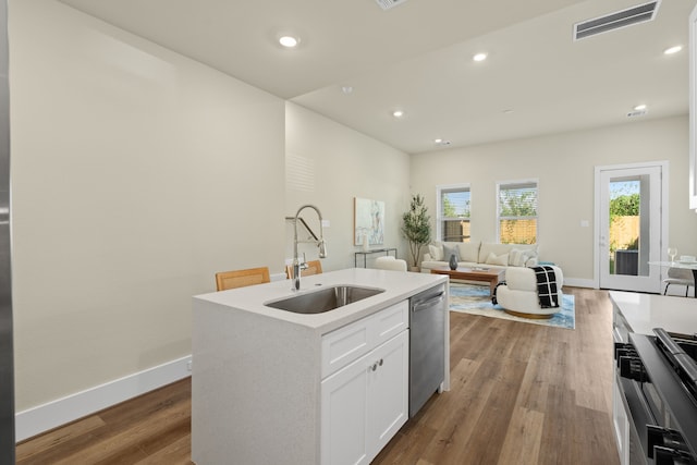 kitchen featuring sink, light hardwood / wood-style flooring, an island with sink, stainless steel appliances, and white cabinets