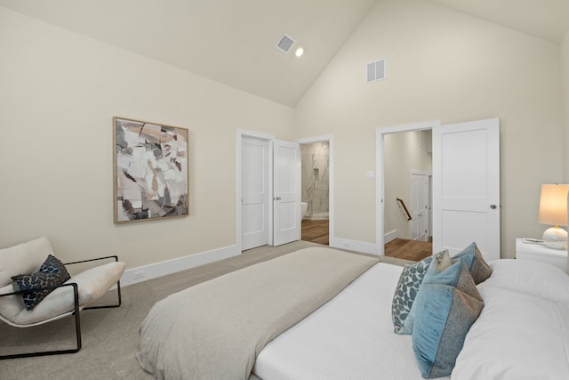 bedroom featuring ensuite bathroom and high vaulted ceiling