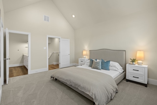 bedroom featuring connected bathroom, light colored carpet, and high vaulted ceiling