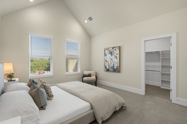 bedroom with light carpet, a walk in closet, and high vaulted ceiling