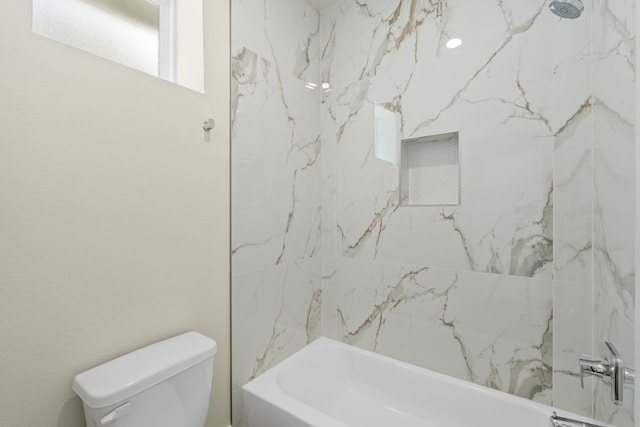 bathroom with tiled shower / bath combo and toilet