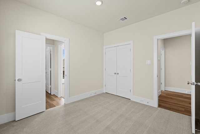 unfurnished bedroom featuring light carpet and a closet