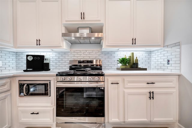 kitchen featuring decorative backsplash, appliances with stainless steel finishes, white cabinetry, and wall chimney range hood