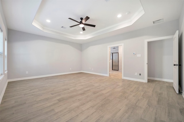 empty room with light wood-type flooring, a raised ceiling, ceiling fan, and ornamental molding