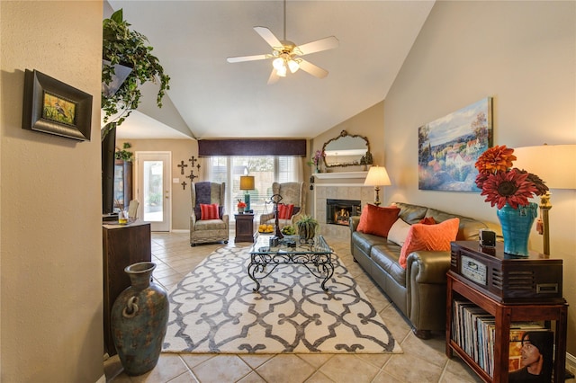 tiled living room with ceiling fan, a tiled fireplace, and vaulted ceiling