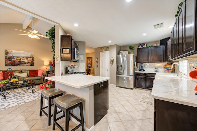 kitchen with a kitchen bar, appliances with stainless steel finishes, tasteful backsplash, sink, and light tile patterned floors