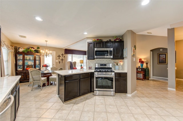 kitchen with kitchen peninsula, appliances with stainless steel finishes, tasteful backsplash, a notable chandelier, and hanging light fixtures