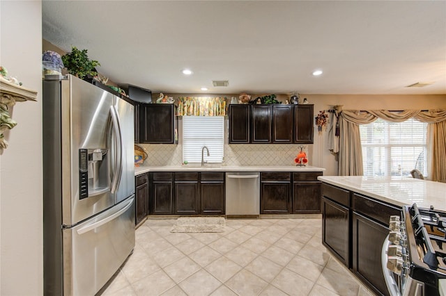 kitchen with dark brown cabinetry, decorative backsplash, sink, and appliances with stainless steel finishes